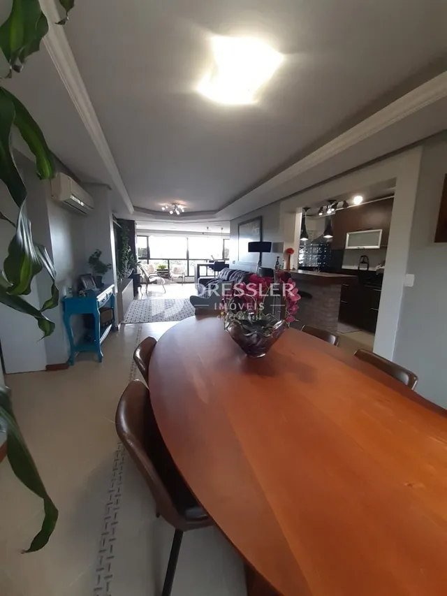 Vista interna de uma sala de jantar com mesa de madeira.
