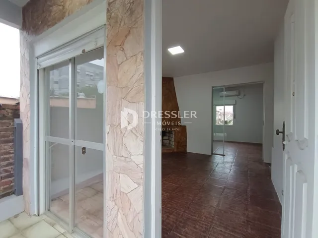 Vista interna de um corredor com parede de pedra e portas de vidro.