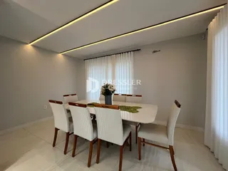 Uma sala de jantar com mesa e cadeiras brancas em um ambiente claro.