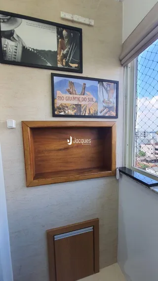 Parede interna com quadros e prateleira de madeira em um imóvel.