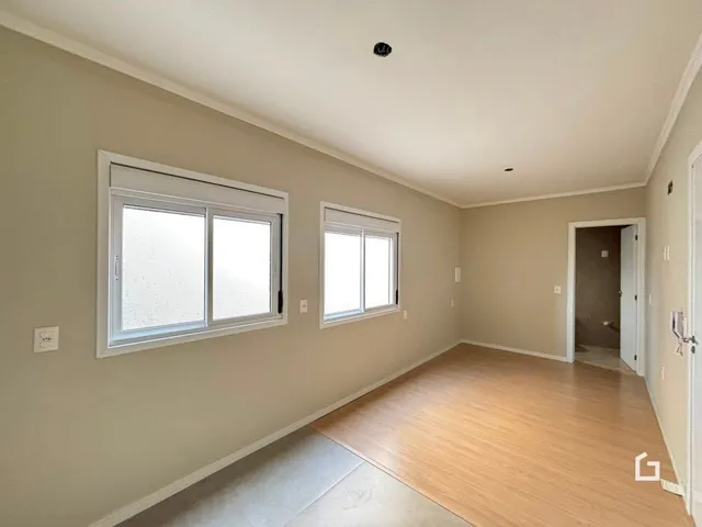 Interior de uma sala com piso de madeira e paredes claras.