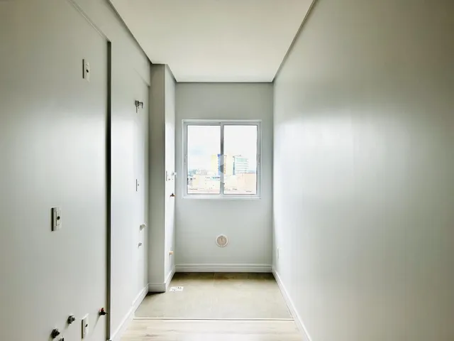 Corredor interno de uma residência com paredes brancas e piso claro.
