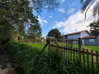Vista externa de uma propriedade rural em Lajeado, Brasil, com cerca de madeira e vegetação exuberante.