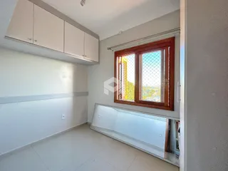 Interior de uma sala com piso claro e janela de madeira em um imóvel no Brasil.