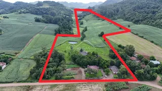 Vista aérea de uma propriedade rural cercada por campos verdes e vegetação.