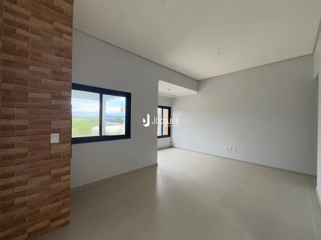 Ambiente interno de uma sala ampla com parede de tijolo aparente.