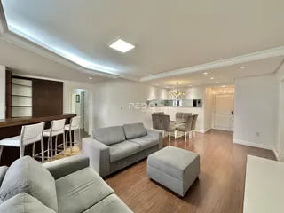 Sala de estar e jantar com piso de madeira e sofá moderno.