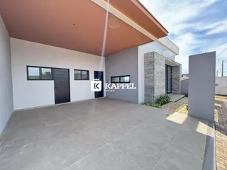 A foto mostra a fachada moderna de uma residência com área externa pavimentada.