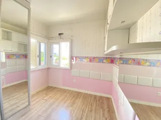 Um quarto com paredes rosa e piso de madeira clara.