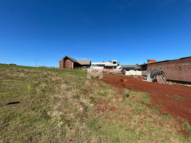 Vista externa de uma propriedade com terreno gramado e estruturas de alvenaria.