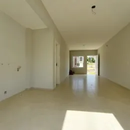 Corredor longo com paredes brancas e piso claro.
