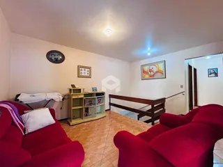 Sala de estar com sofás vermelhos e piso de madeira clara.
