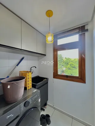 Foto de uma cozinha com armários brancos e janela de madeira.