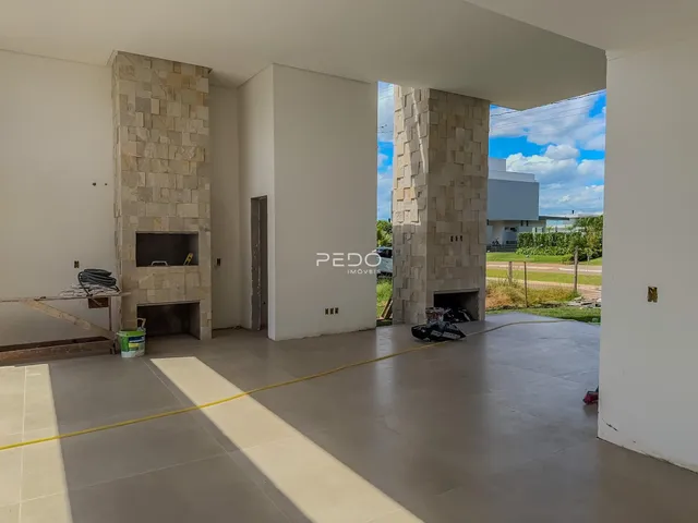 Vista interna de um ambiente com paredes brancas e colunas de pedra em uma residência.