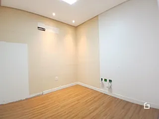 Foto de um ambiente interno com piso de madeira clara e paredes brancas.
