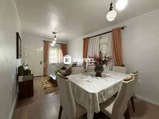 Foto de um ambiente de jantar com mesa e cadeiras brancas em uma sala clara.