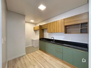 Vista interna de uma cozinha com armários de madeira e piso de madeira clara.