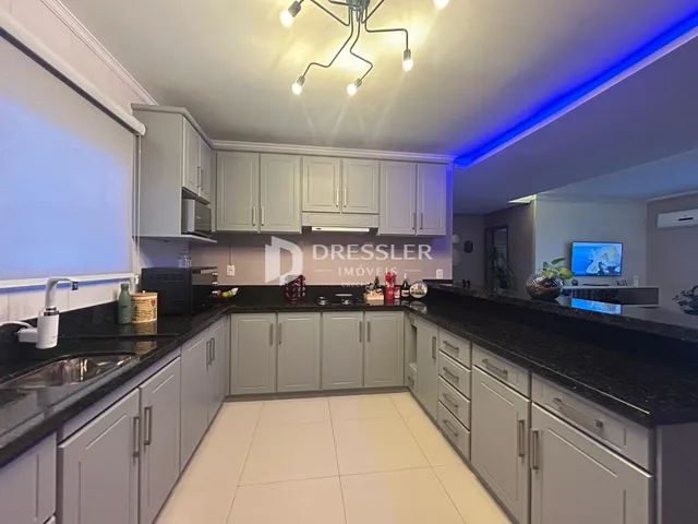 Vista da cozinha com armários cinzas e bancadas escuras.