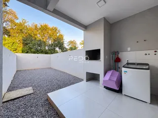 Vista externa de um pátio com piso de concreto e muro branco.