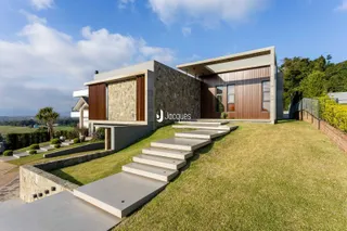 Fachada moderna de uma residência em Lajeado, Brasil, com jardim e escadaria de concreto.