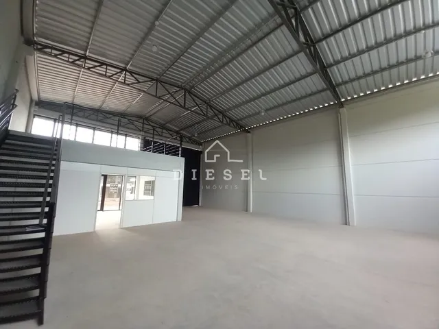 Interior de um espaço industrial com teto de metal e portas de garagem.