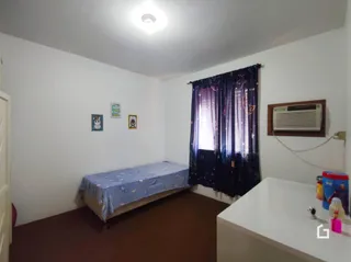 Quarto com cama e cortinas escuras em uma residência.