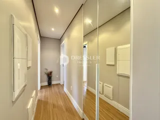 Hall de entrada com piso de madeira clara e paredes neutras.