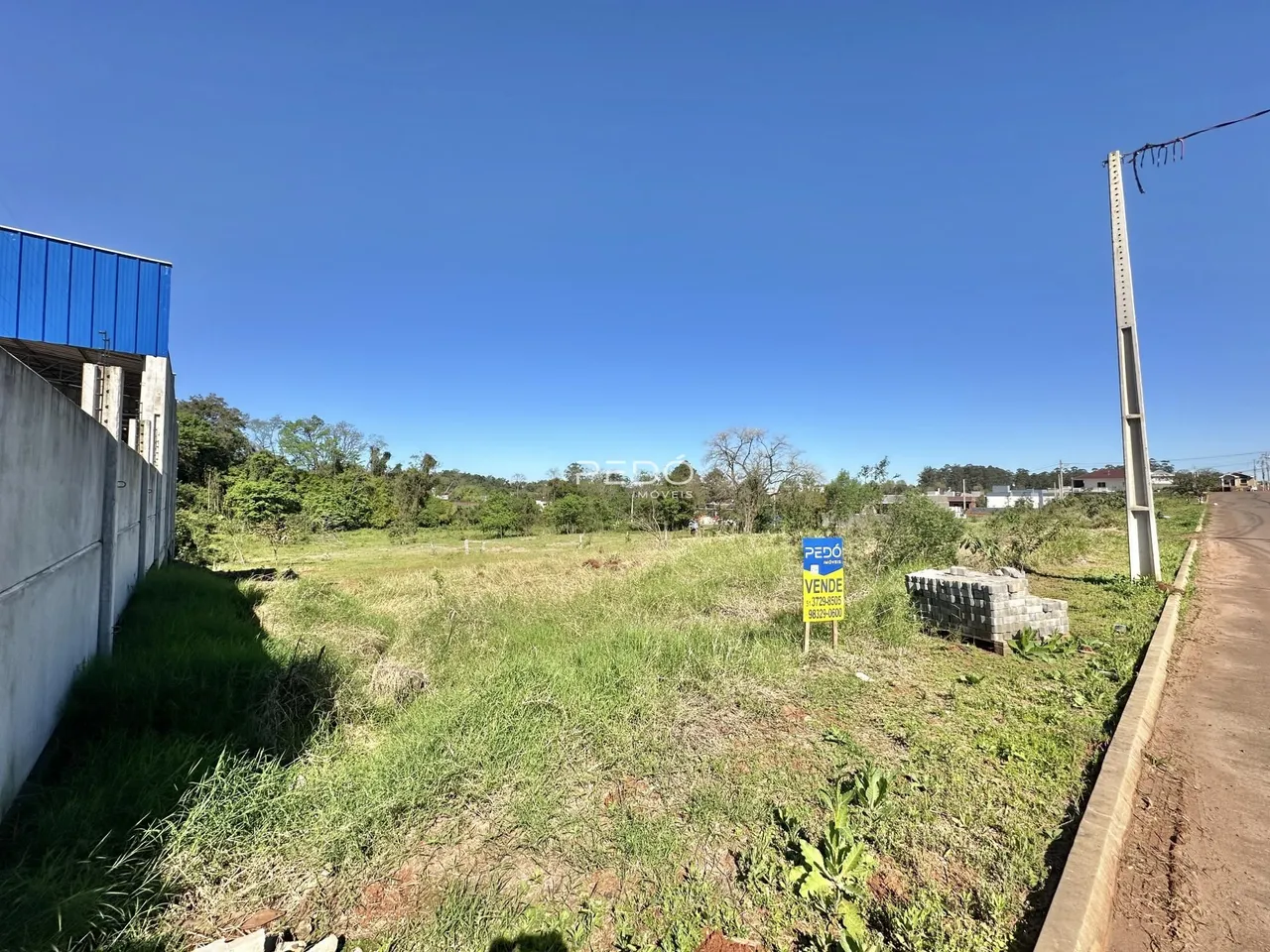 Parede de concreto e campo de grama em uma propriedade rural.