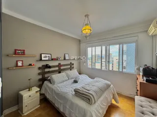 Quarto com cabeceira de madeira e janela com vista para a cidade.