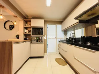 Interior de uma cozinha moderna com armários brancos e bancadas escuras.
