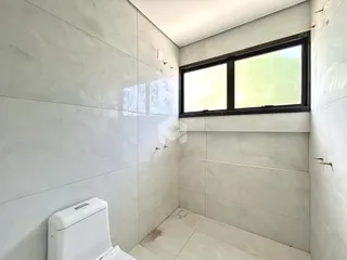 Banheiro com paredes e piso de cerâmica branca.