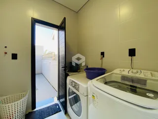 Foto de um cômodo interno mostrando uma máquina de lavar e uma porta de acesso.