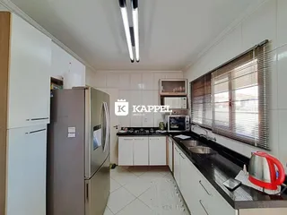 Cozinha com armários brancos e bancada preta em ambiente bem iluminado.