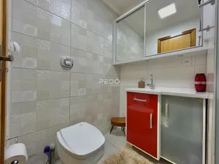 Foto interna de um banheiro com revestimento cerâmico e louças sanitárias brancas.