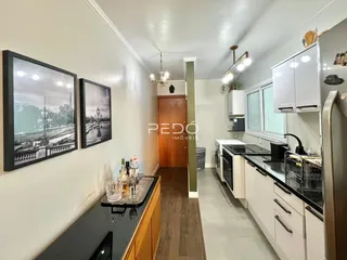Cozinha moderna com armários brancos e bancadas escuras.