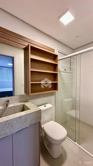 Foto de um banheiro com box de vidro e bancada de granito.