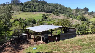 Vista externa de uma estrutura rústica em uma área de colina com vegetação densa.