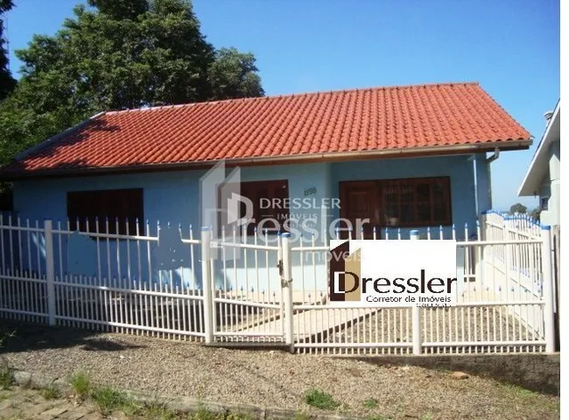 Fachada de uma casa com telhado de telhas vermelhas e cerca branca.