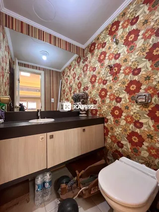 Banheiro com revestimento de parede floral e bancada de madeira.