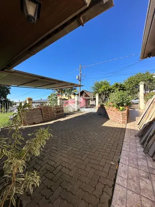 Área externa pavimentada com tijolos e vegetação.