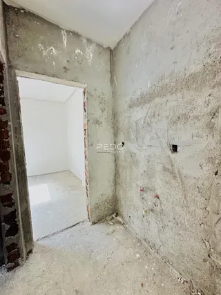 Interior de um cômodo com paredes de alvenaria crua e teto de gesso.