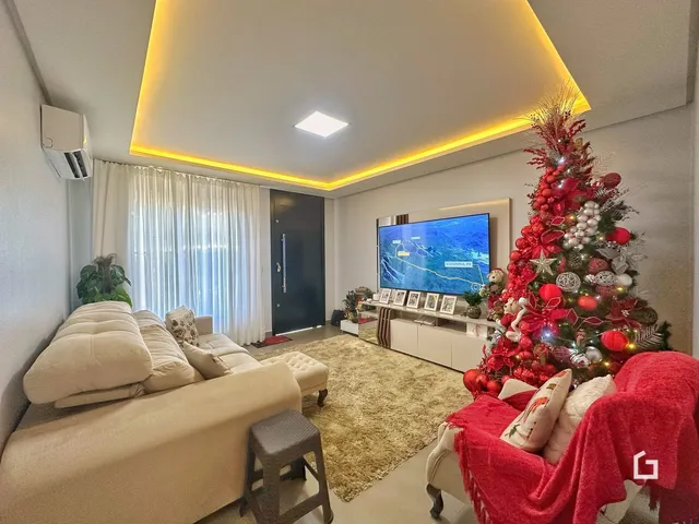 Sala de estar com sofá claro e árvore de Natal decorada.
