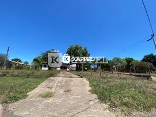 Vista externa de uma estrada de terra com vegetação ao redor da propriedade.