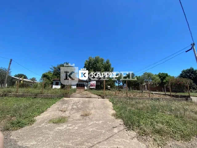 Vista externa de uma estrada de terra com vegetação ao redor da propriedade.
