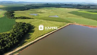 Vista aérea de uma propriedade rural com extensos campos verdes e um corpo d'água.
