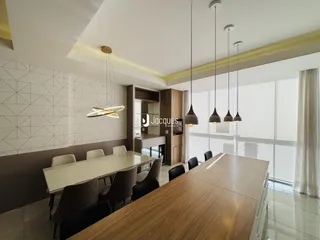 Sala de jantar moderna com mesa de madeira e iluminação pendente.