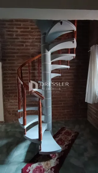 Hall com escadaria moderna e parede de tijolos na residência.