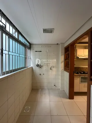 Corredor interno com paredes de azulejo e janela grande em um imóvel.