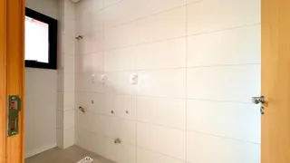 Parede de um corredor interno com revestimento cerâmico branco.
