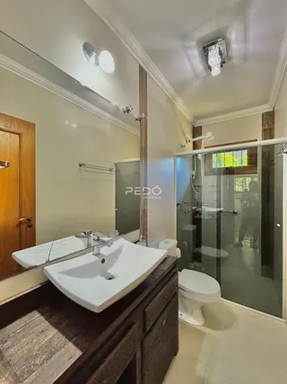 Foto de um banheiro com pias e box de vidro.